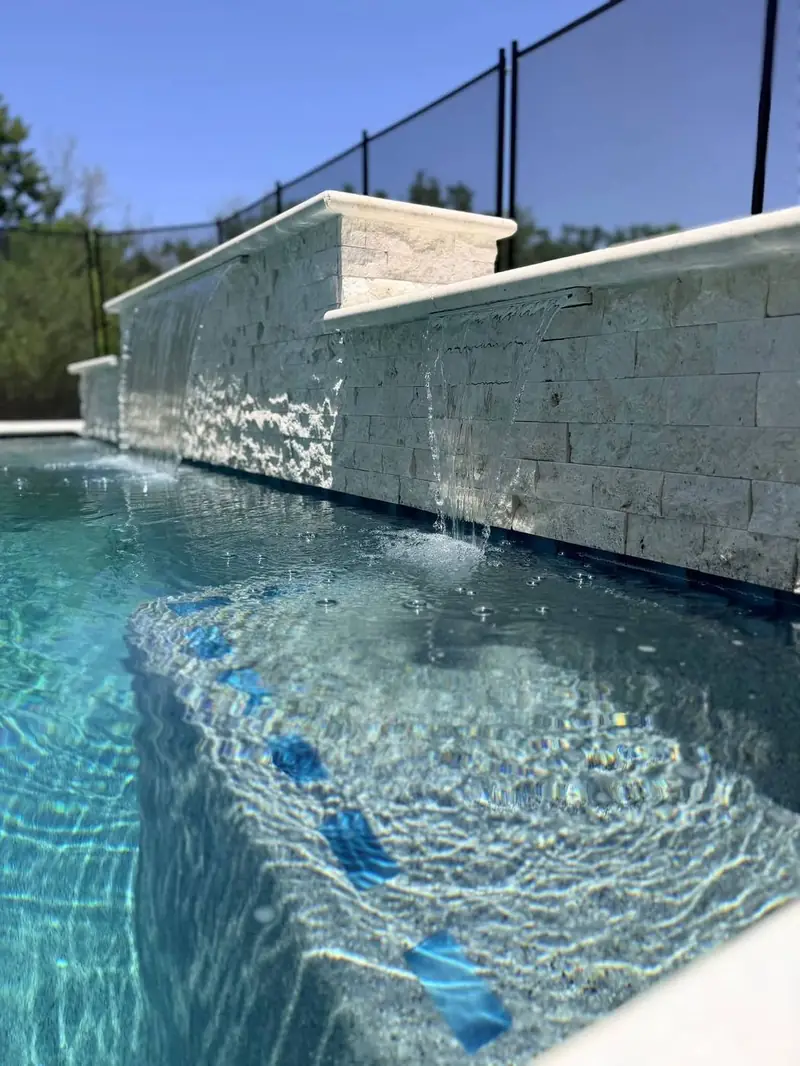 Twin sheer descent waterfalls over a stacked travertine wall